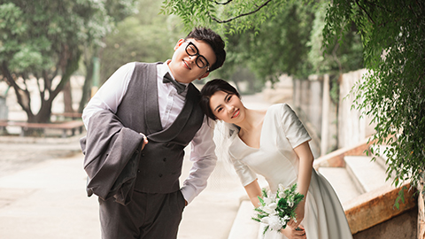 Wenshi and Ruilin wear wedding attire and are pictured outdoors leaning on each other